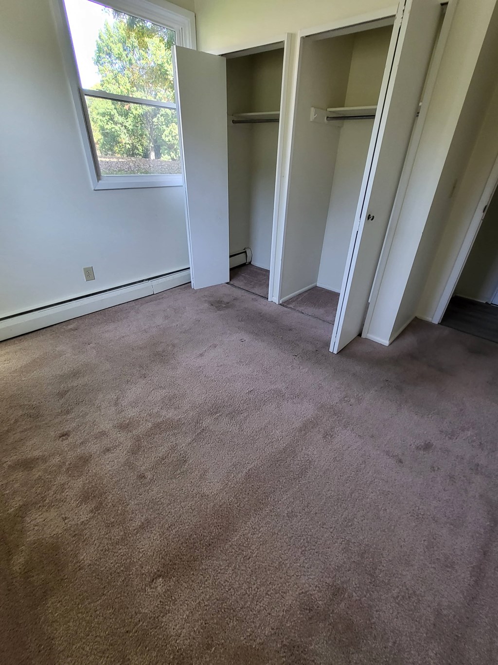 a carpeted room with open doors and a window