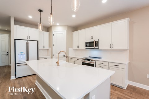 A modern kitchen with white cabinets and a white island.