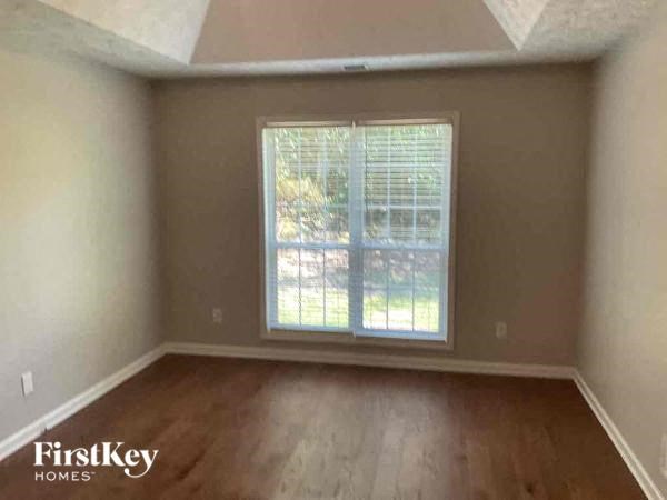 an empty bedroom with a window and wooden floors