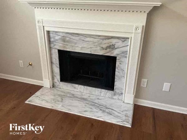 a marble fireplace in a living room with a wooden floor