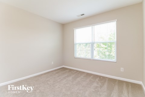 a bedroom with a large window and a carpeted floor
