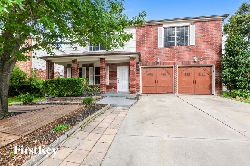 a brick house with two garage doors and a driveway