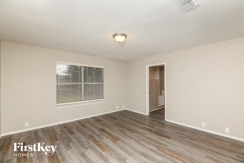 the spacious living room with hardwood flooring and a window