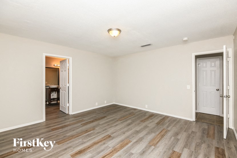 the living room of an apartment with wood flooring and white walls