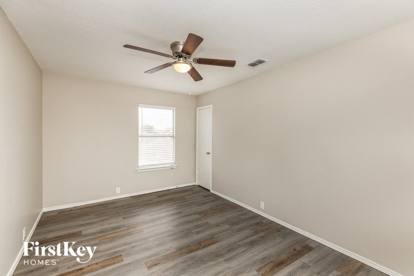 the spacious living room with wood flooring and a ceiling fan