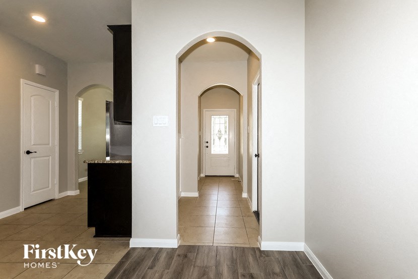 a hallway with an arched door way and white walls and wood floors