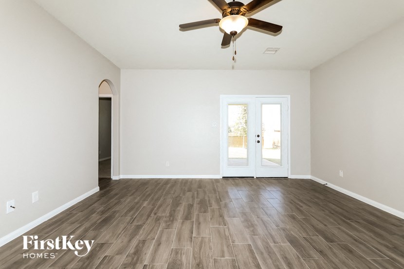 the spacious living room with hardwood flooring and a ceiling fan