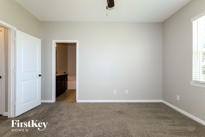 a bedroom with a carpeted floor and a door to a bathroom
