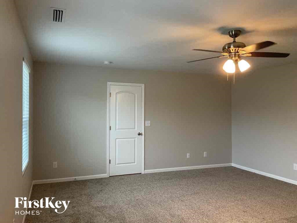 an empty gray room with a ceiling fan and a door