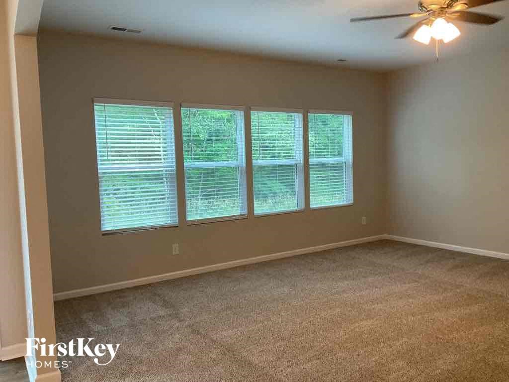 an empty living room with four windows and a ceiling fan