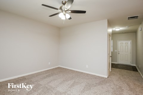 A spacious room with a ceiling fan and a carpeted floor.