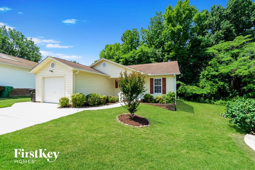 a white house with a lawn and a tree in front of it