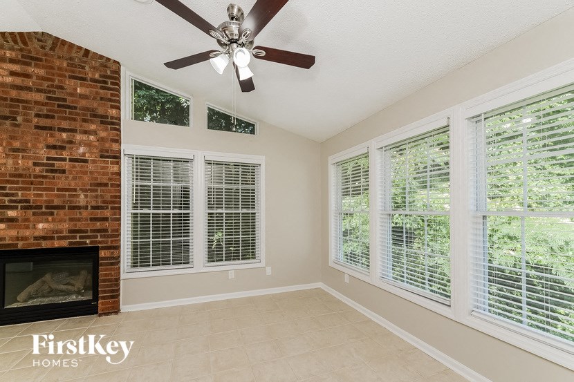 an empty living room with a brick fireplace and a ceiling fan