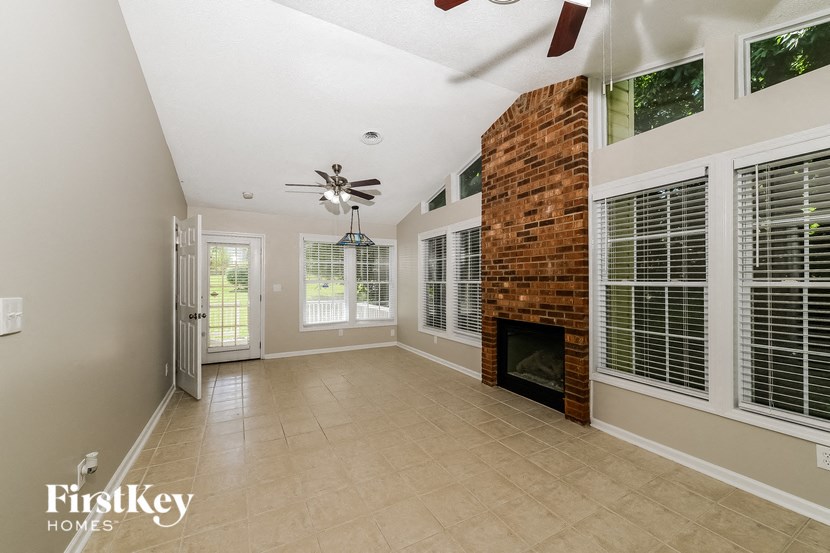 an empty living room with a brick fireplace and a ceiling fan