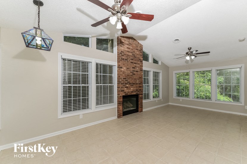 an empty living room with a fireplace and a ceiling fan