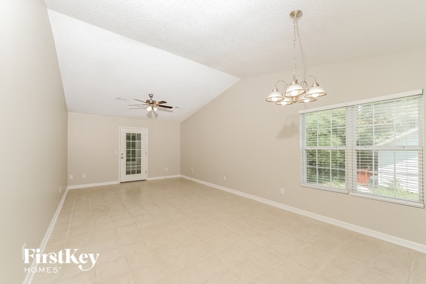 an empty living room with a large window and a ceiling fan