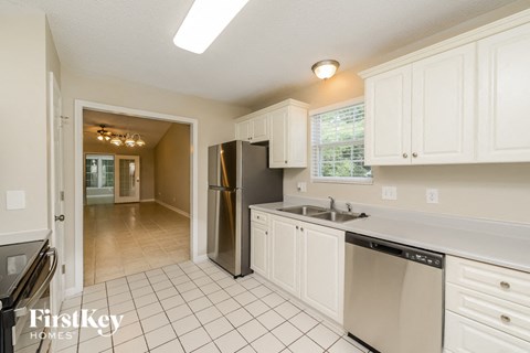 a kitchen with white cabinets and a sink and a refrigerator