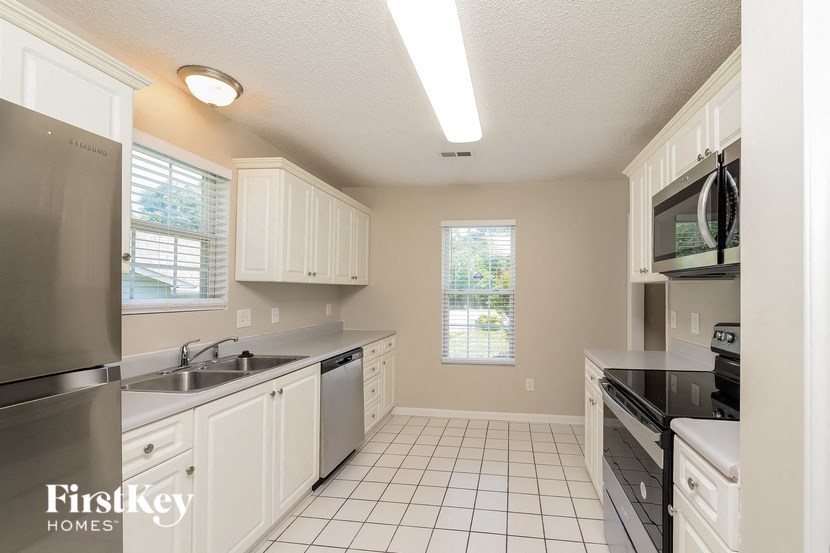 a kitchen with white cabinets and black counter tops