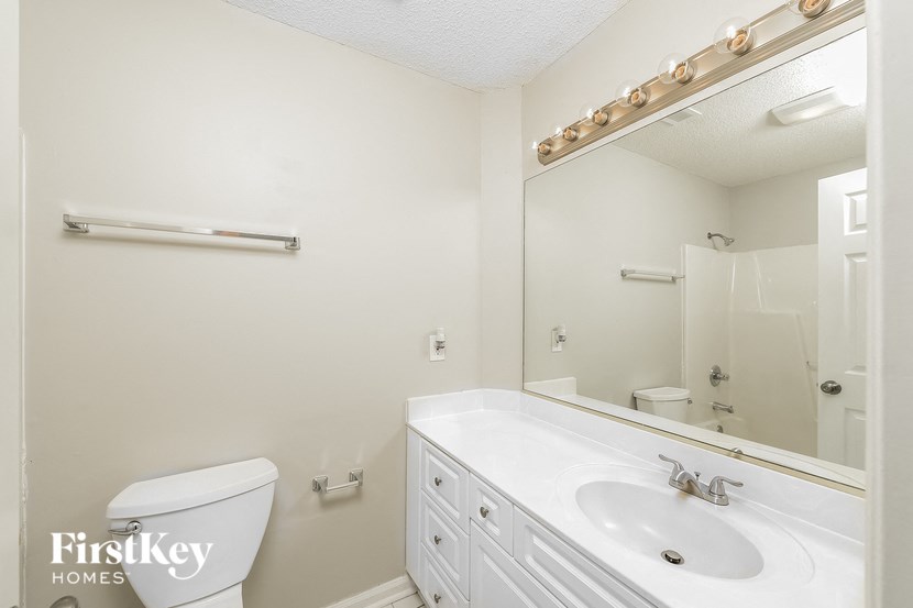 a white bathroom with a sink toilet and mirror
