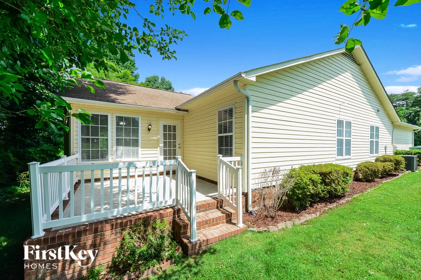 a small yellow house with a porch and a green lawn