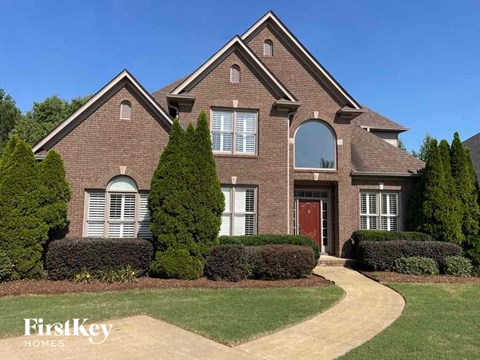 the front of a brick house with a red front door