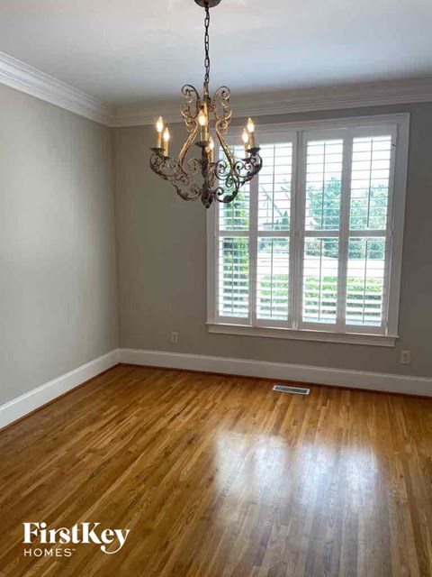 an empty living room with a chandelier and a window