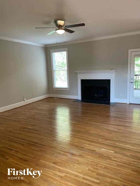 an empty living room with a ceiling fan and a fireplace