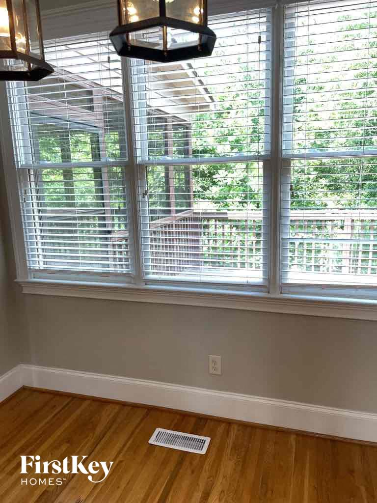 a living room with three windows and a wood floor