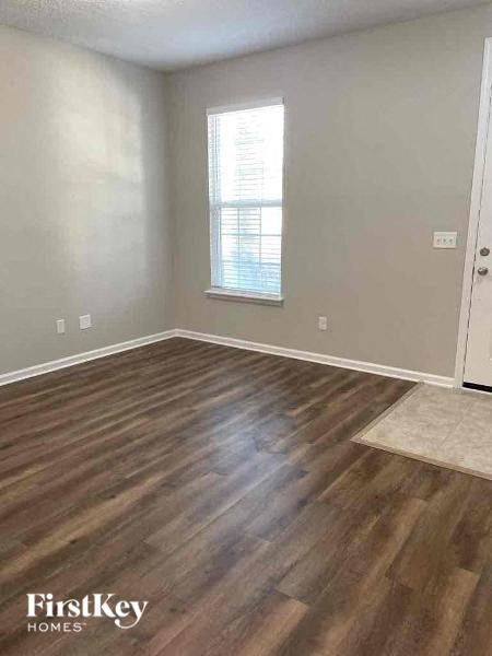 an empty living room with wood floors and a window