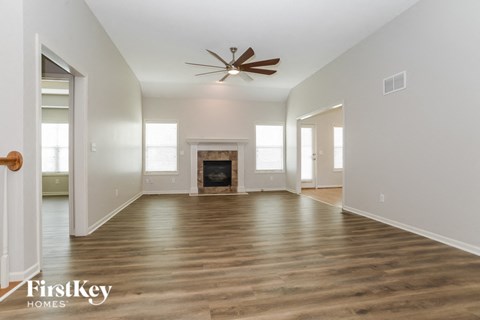 A spacious room with a fireplace and a ceiling fan.