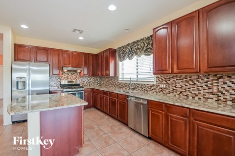 A kitchen with brown cabinets and a marble countertop.