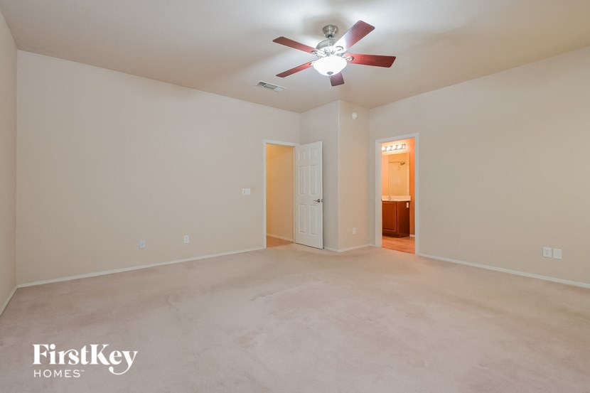 A spacious empty room with a ceiling fan and two doors.