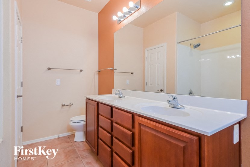 A bathroom with a toilet, sink, and mirror.