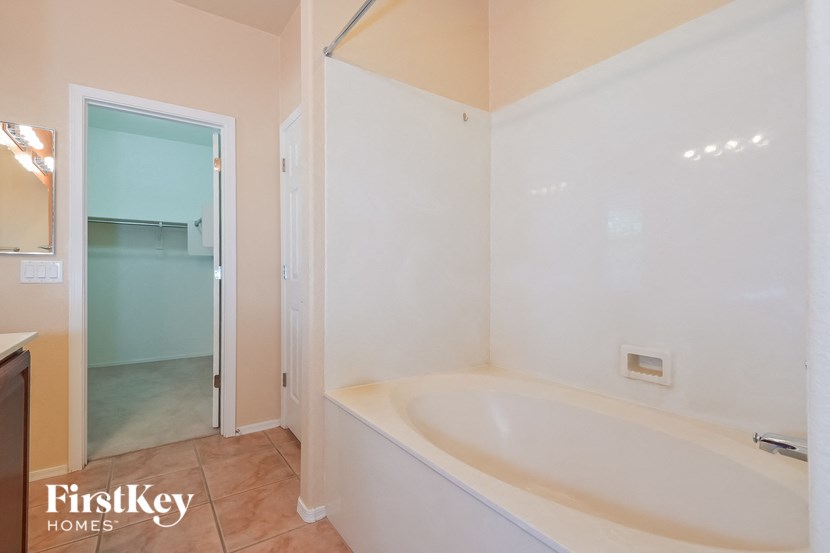 A white bathroom with a bathtub and a glass door.