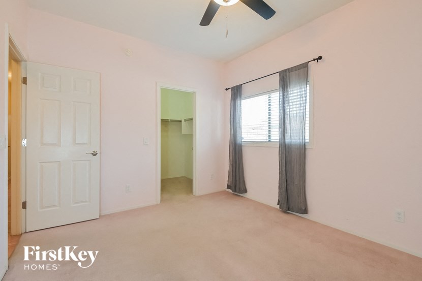 A room with a fan and a window with curtains.