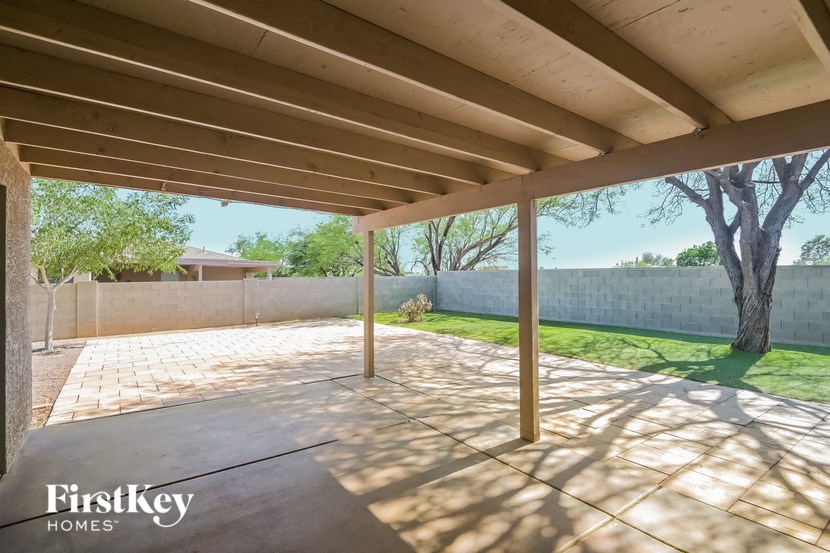 A patio area with a concrete floor and a wooden pergola.