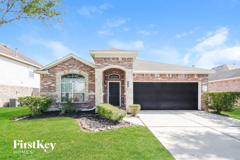 a brick house with a driveway and a black garage door