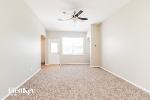 a spacious living room with carpet and a ceiling fan