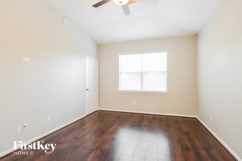 the spacious living room with hardwood flooring and a ceiling fan