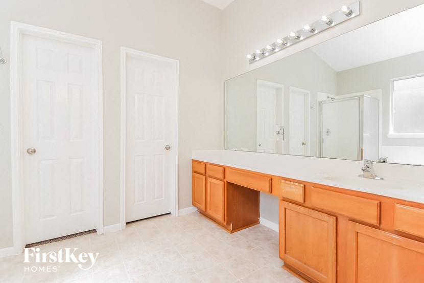 a bathroom with a large mirror and a large vanity with wooden cabinets