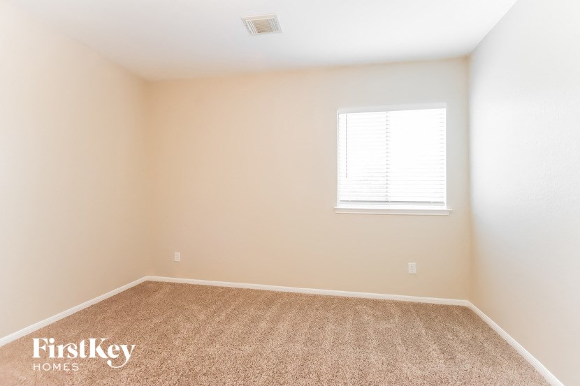 a bedroom with a window and a carpeted floor