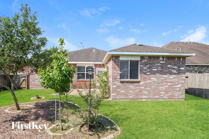 the backyard of a brick house with a yard and trees