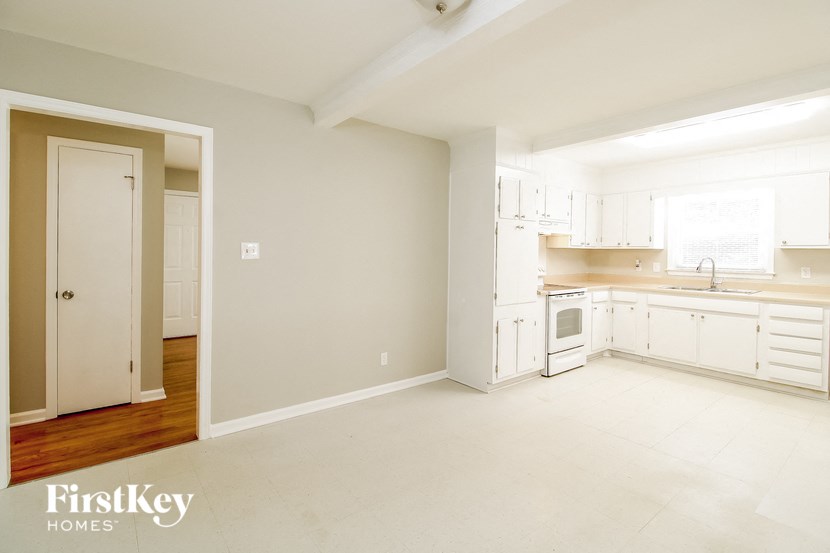 an empty kitchen with white cabinets and a door way
