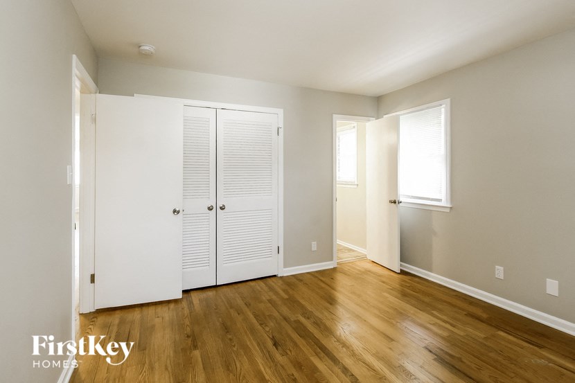 an empty room with white closets and wood floors