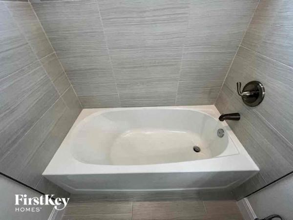 a white bath tub in a bathroom with white tiles