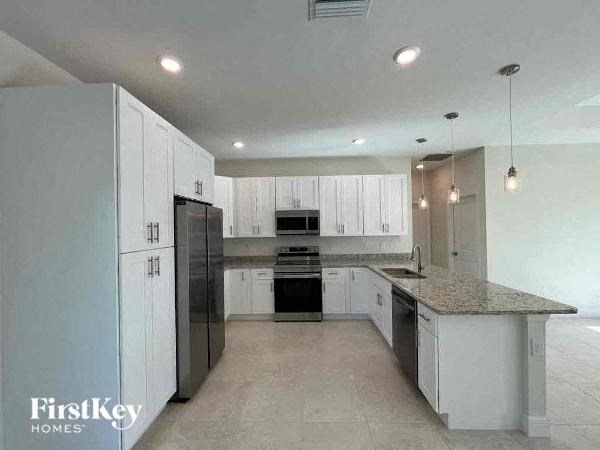 a large kitchen with white cabinets and black appliances