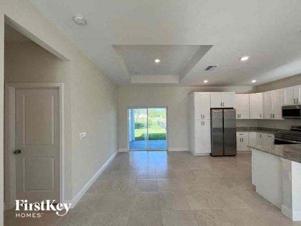 a large empty kitchen with a refrigerator and a sink