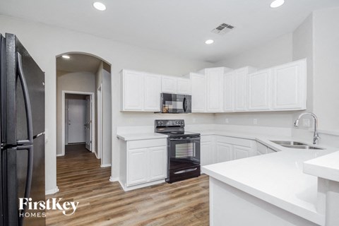 A kitchen with white cabinets and a black oven.