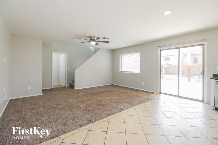 A spacious room with a carpeted floor and a ceiling fan.