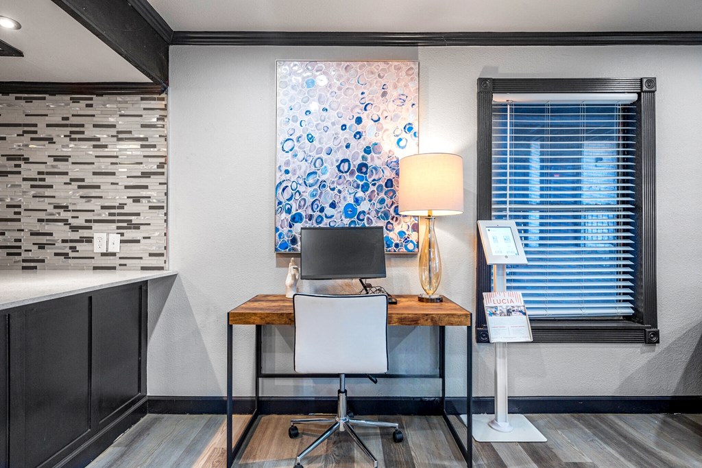 a desk with a computer and a lamp in a room with a window